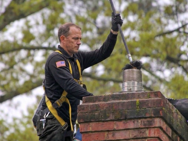 Chimcare technician sweeping a chimney from the roof