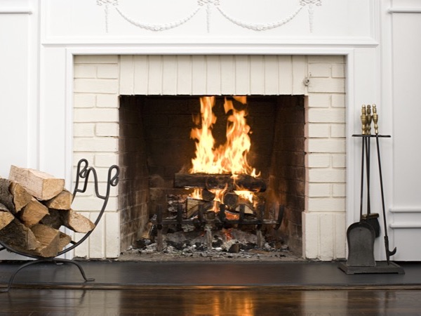 Wood burning insert with a fire lit in a brick hearth