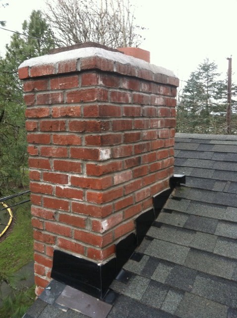 A clean red brick chimney with new black flashing after repair A clean red brick chimney with new black flashing after repair