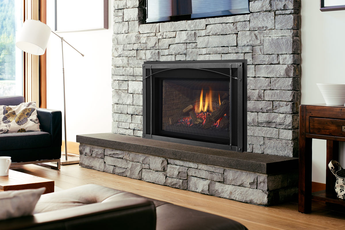 A Liberty Radiant Large gas insert in a stacked stone fireplace with a raised hearth