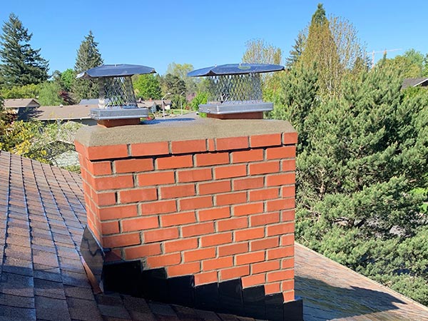A rebuilt brick chimney with new chimney caps after repair