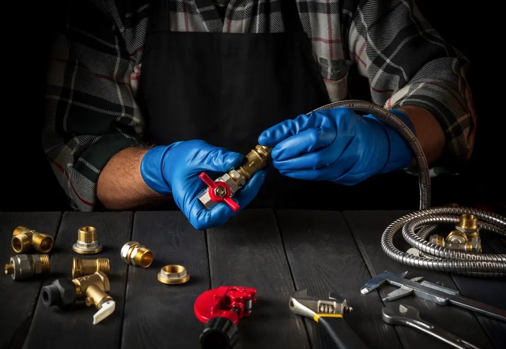 A technician in blue gloves preparing brass gas fittings and flexible gas line A technician in blue gloves preparing brass gas fittings and flexible gas line